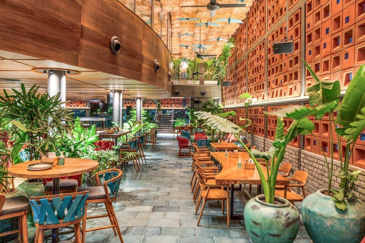 Tropical dining area with wooden tables and plants at Makau